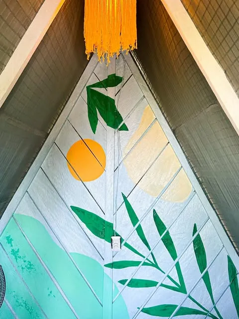 Pintura de folhagens verdes e sol amarelo no gable de madeira de um chalé