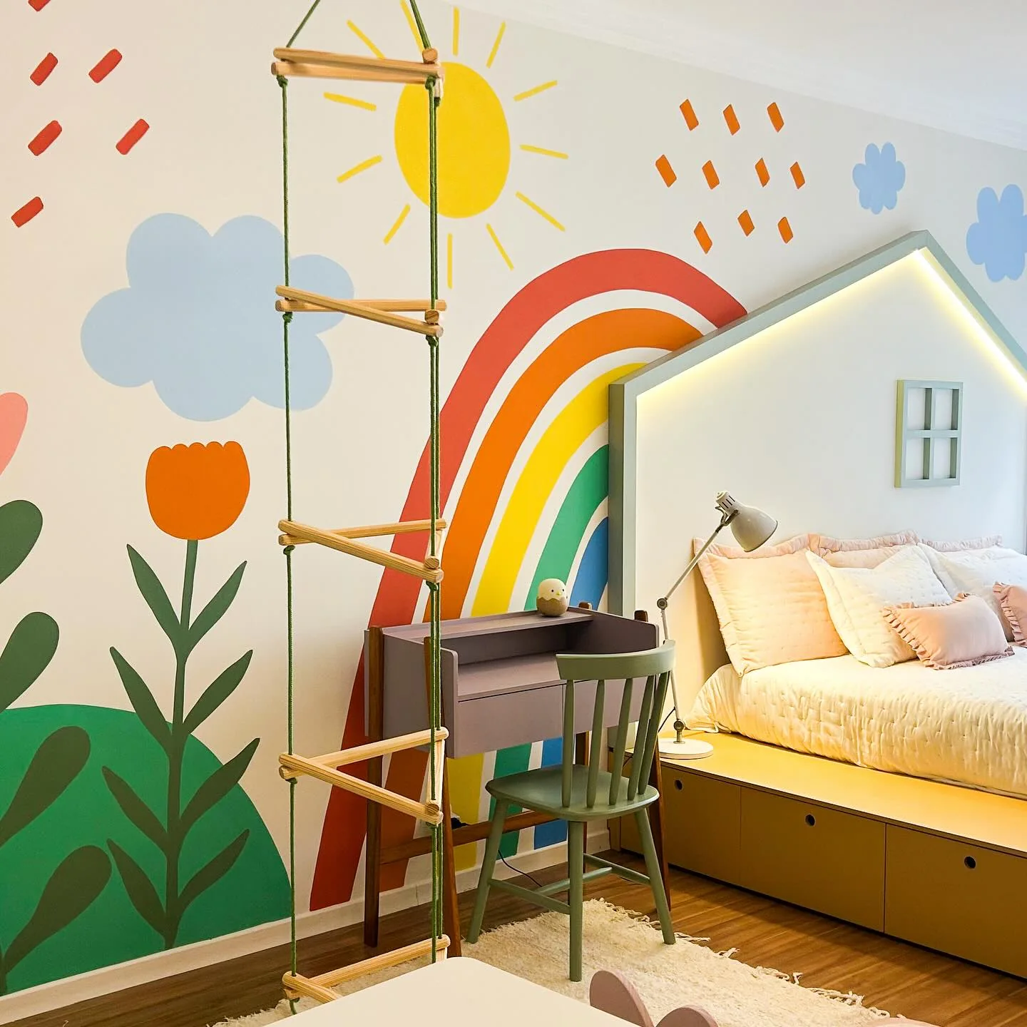 Mural colorido com arco-íris, sol, nuvens e flores em quarto infantil