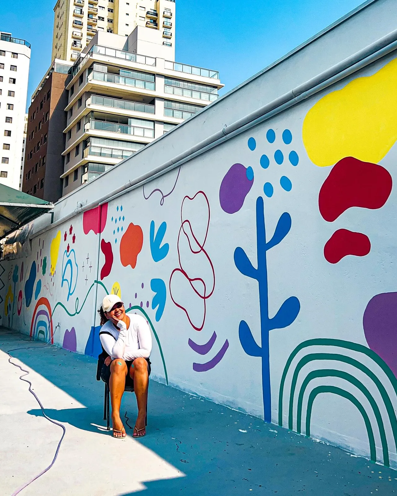 Mural externo com formas coloridas, plantas e arco-íris