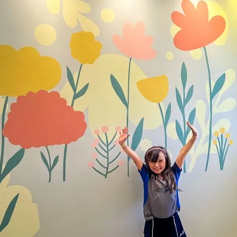 Mural de flores coloridas em tons de amarelo, coral e azul petróleo em parede clara
